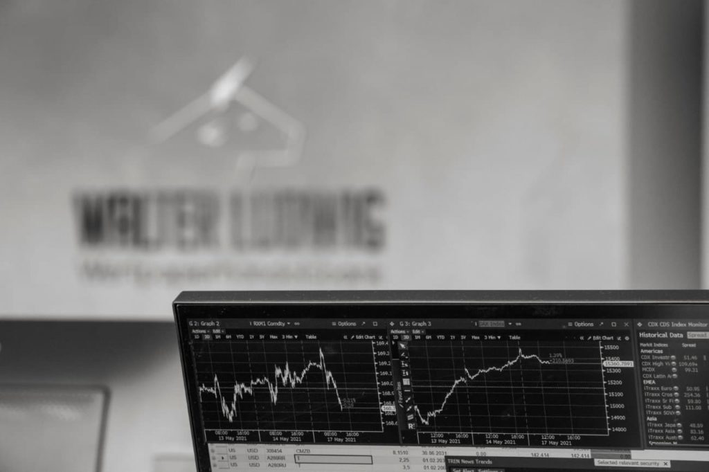 Entwicklungsdiagramm eines Wertpapiers auf dem Computerbildschirm. Im Hintergrund das Logo der Walter Ludwig GmbH Wertpapierhandelsbank